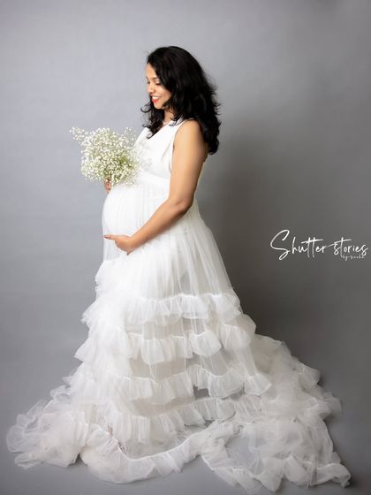 An angelic look for a mom-to-be. This full-length portrait in a white ruffled gown against a clean grey backdrop creates a timeless and elegant maternity photo.