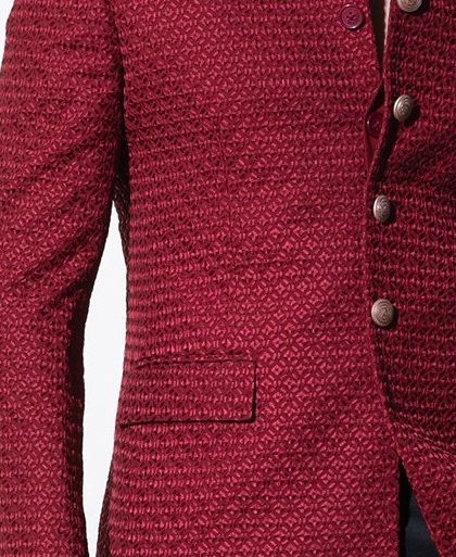 Another close-up of the crimson bandhgala's unique fabric. This view highlights the meticulous weave and rich color that define this standout piece of formalwear.