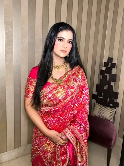 A full shot of the client, her red saree and gold jewelry a classic combination.