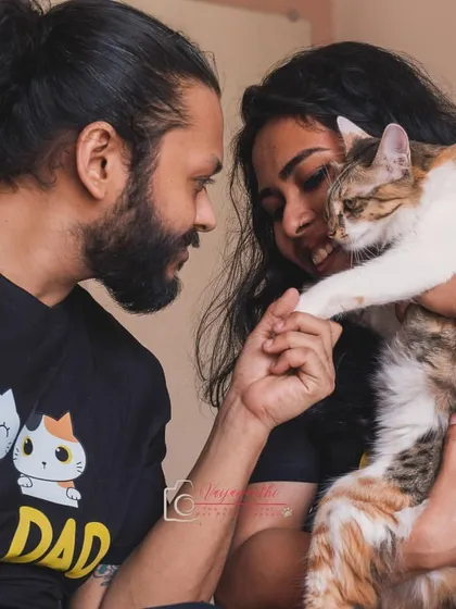 A beautiful family portrait with their calico cat, Hermione. The "Cat Dad" shirt and the gentle way they hold her paw tells a story of a truly cherished pet.