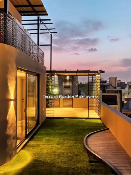 This rooftop design combines lush artificial grass with a curved wooden walkway, leading to a seating area. The combination of textures creates visual interest and defines the different zones of the terrace.