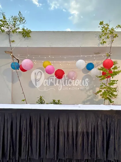 A simple yet effective decoration of colorful paper lanterns and fairy lights strung up for an evening celebration.