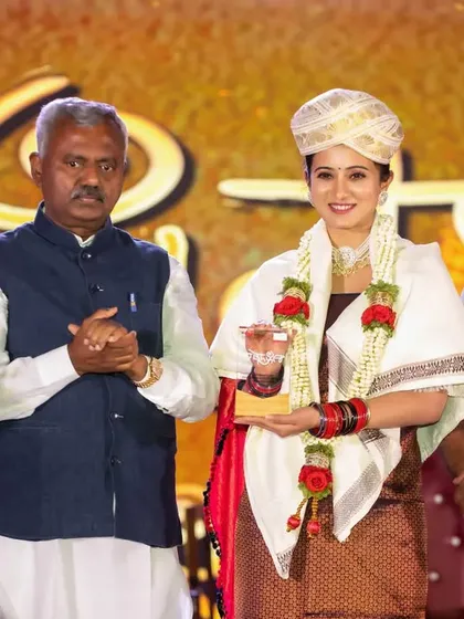 Actress Harshika Poonacha receiving an award on stage. We focus on capturing the expressions of honorees and presenters, providing our clients with memorable images from their corporate functions.