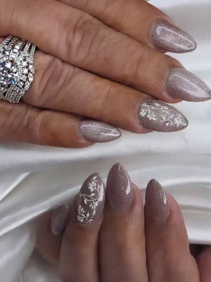 A sophisticated and royal look for a bride. These nails feature a shimmering brown cat-eye polish with delicate, hand-painted white floral details, perfect for an elegant wedding theme.