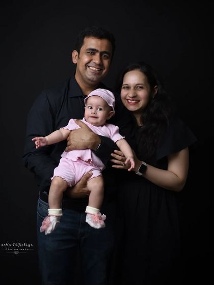A classic family portrait against a dark backdrop. The simple background and coordinated dark clothing ensure that the family's happy faces are the main focus of the photograph.