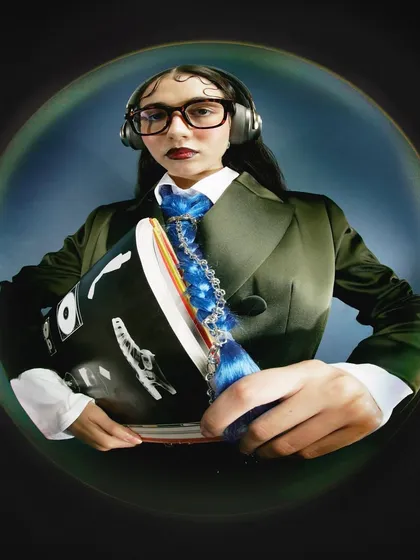 A variation of the suited look, with the model presenting the book towards the camera. The composition draws the viewer's eye to the props and the distorted hands.