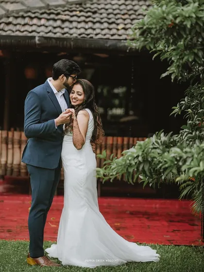 A tender moment as the groom kisses his bride's forehead in a lush garden.
