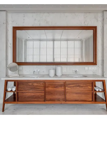 A custom-designed vanity in the Bombay Penthouse. The combination of salvaged teak, white Bhanswara marble, and a clean, mid-century inspired design creates a sense of peaceful, elemental luxury.