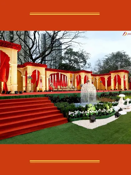 A grand and regal outdoor setup in shades of red and gold. The long arcade of arches and a central fountain create a palatial atmosphere for a traditional wedding.