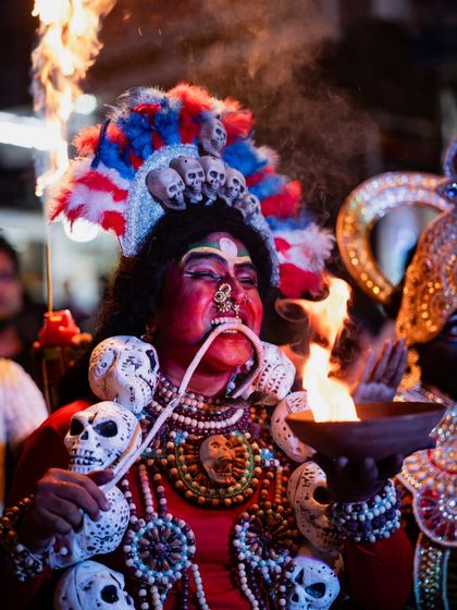This shot captures the performer in a moment of ritual, with fire and smoke adding to the dramatic atmosphere of the street festival.