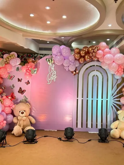 A grand 'Oh Baby' shower with a butterfly theme. This stage features a large pastel purple backdrop, butterfly wing-shaped balloon arrangements, and cute teddy bears for a whimsical touch.