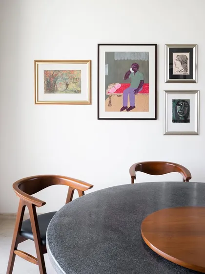 A closer look at the dining space where my custom furniture coexists with the client's art collection. The dark terrazzo tabletop and the curved teak chairs were designed to create a sophisticated yet inviting atmosphere for meals.