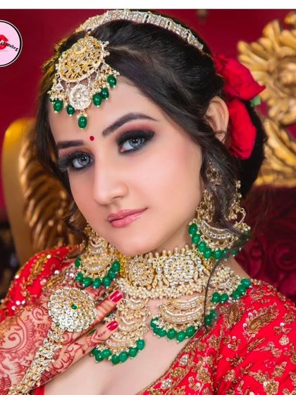 A close-up of a bride wearing a beautiful Kundan and emerald set. The red roses in her hair add a touch of classic romance to the look.
