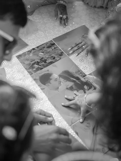 A touching, candid moment captured in black and white. Family members gather to look at old photographs, reminiscing about the couple's journey together during a heartfelt Haldi ceremony.