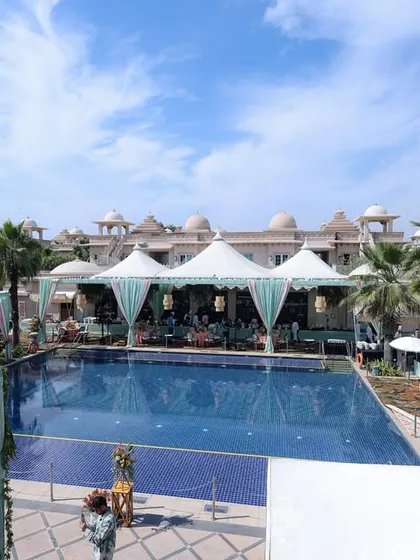 A wide shot of the poolside venue, showing the elegant white tents and aqua-draped canopies that created a chic and comfortable environment for the daytime celebration.