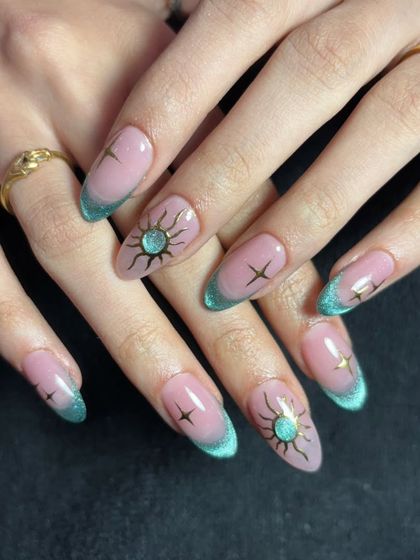 A similar celestial theme, this time with a teal cat-eye French tip and gold sun and star accents.