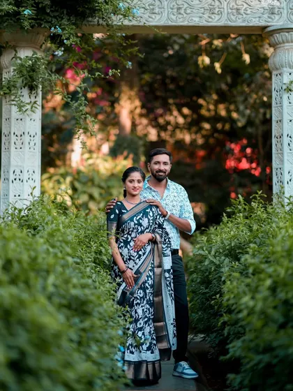 A happy couple posing in a garden archway. Their traditional outfits and the natural surroundings create a fresh and timeless pre-wedding photo.