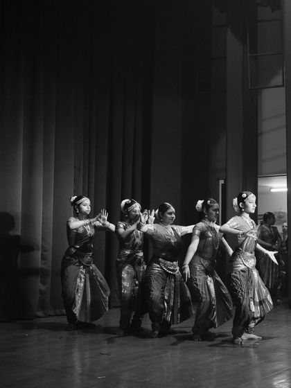 A black and white photograph capturing the timeless elegance of Bharatanatyam. The synchronized movement of the dancers creates a beautiful visual rhythm.