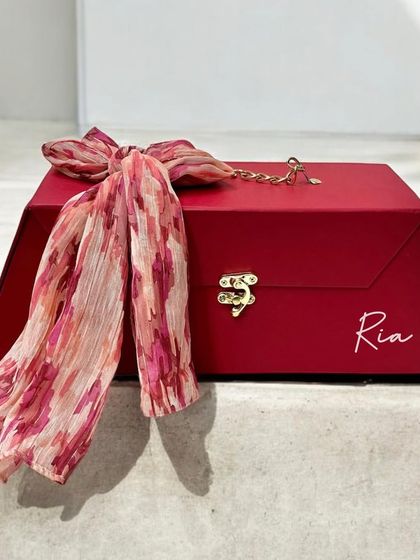 This sophisticated red gift trunk is personalized with the name 'Ria'. It's elegantly finished with a printed scarf tied around the handle, making for a very special keepsake box.