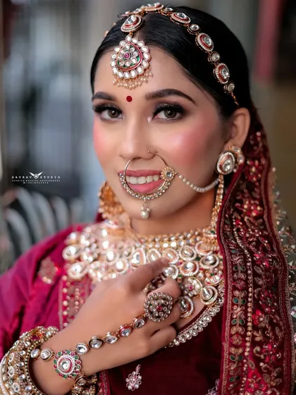 A beautiful close-up portrait of the smiling bride, showcasing her nath and maang tikka.