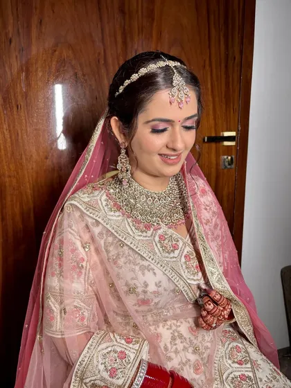 A side profile showcasing the elegant hair and makeup. The look is completed with a delicate bindi and traditional red bangles, tying everything together beautifully.