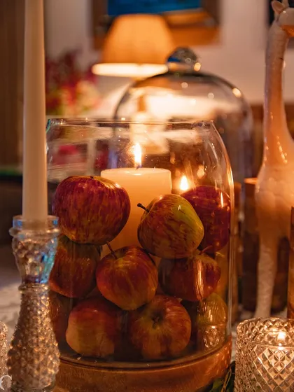 I often use natural elements in unexpected ways, like surrounding a pillar candle with fresh apples inside a glass hurricane. This adds a rustic yet sophisticated touch to the luxury event decor.