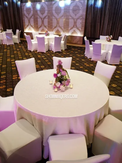 Clean and classic guest seating arrangement for a large dinner. Round tables with simple white linens and chair covers create a uniform and elegant look, allowing the centerpieces to stand out.