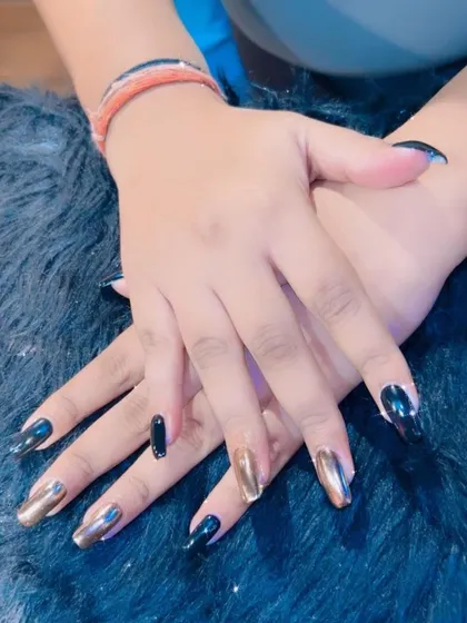 A unique set combining black nails with accent nails in a dual-tone gold and silver chrome finish.