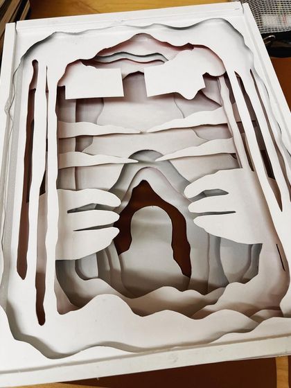 The raw, uncolored paper layers of the sculpture, showing the intricate cutting and structural planning involved.