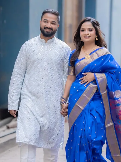 A beautiful moment between the couple during their engagement photoshoot. The bride's traditional blue Paithani is complemented by a natural, glowing makeup look.