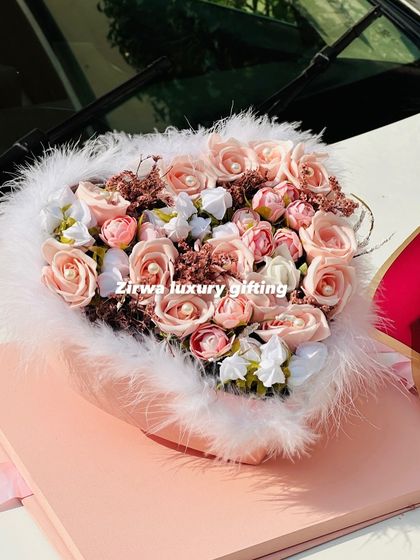 A close-up of one of my most romantic creations. This heart-shaped floral arrangement is trimmed with soft white feathers, making it a truly unique and beautiful Valentine's gift.