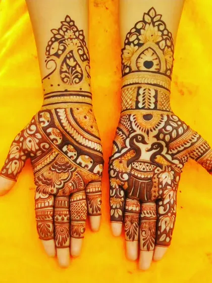 This design combines several classic elements. One hand features kissing peacocks, while the other has an elephant, all tied together with beautiful circular patterns.