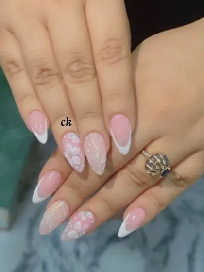 A beautiful set combining a classic white French manicure with accent nails featuring a glitter base and 3D floral details.