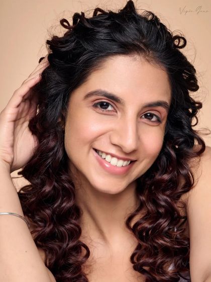 A playful and natural pose from a beauty session. The hand gently touching the hair adds a sense of movement and ease to the portrait.