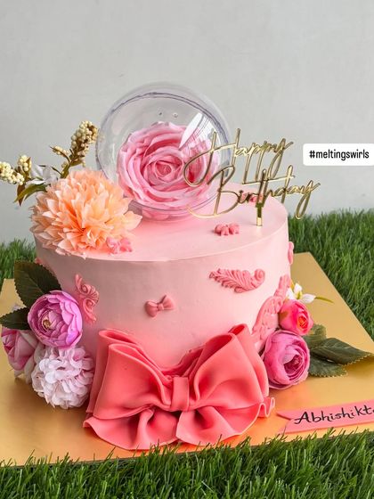 A different angle of the pink floral bow cake, highlighting the intricate details of the handmade fondant bow and the arrangement of flowers.