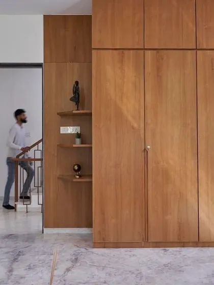 This image shows a real-life custom wardrobe solution integrated into a bedroom. The clean lines of the floor-to-ceiling wooden cabinets provide a massive amount of storage while maintaining a minimalist aesthetic.