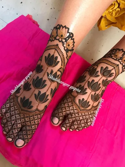 A unique bridal foot design with bold, graphic lotus flowers. The contrast between the dark-filled flowers and the delicate net pattern on the toes is modern and beautiful.