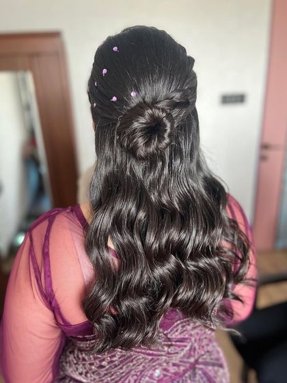 A clear view of the half-up bun with soft waves. This style combines the elegance of an updo with the relaxed feel of open hair, making it a popular choice for many occasions.