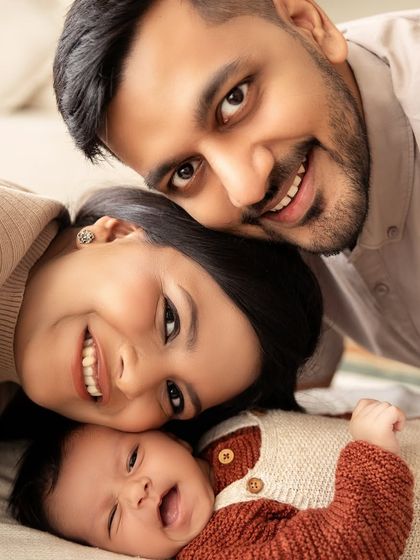 A fun family moment, with everyone lying down together and the baby giving a big, expressive yawn.