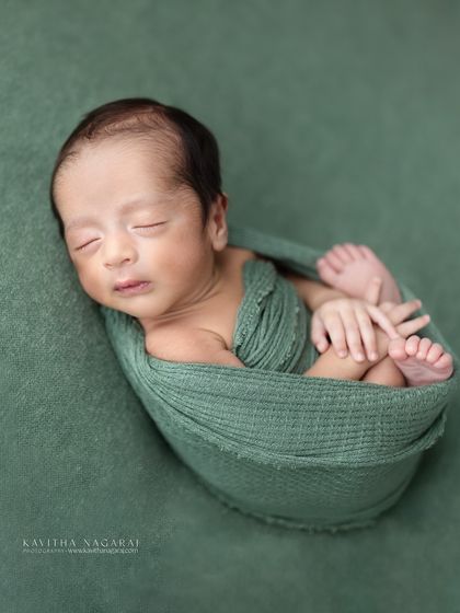 Introducing Aryan, just one week new. This portrait captures him peacefully wrapped in a green swaddle, showcasing the delicate, fresh look of a baby in their first ten days.