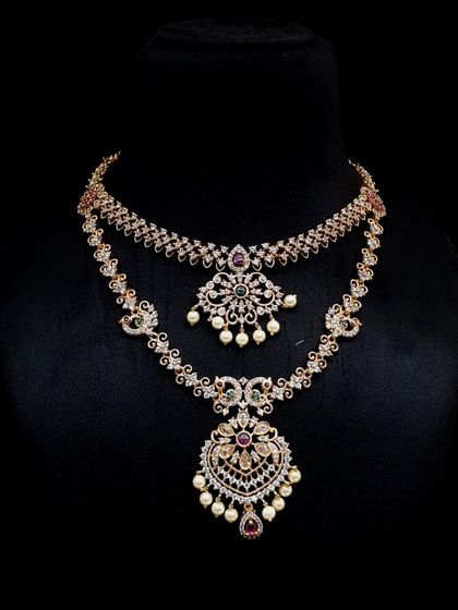 A delicate double-layered necklace set with AD stones and pearl drops. The intricate design features peacock motifs, making it a graceful choice for receptions or engagements.