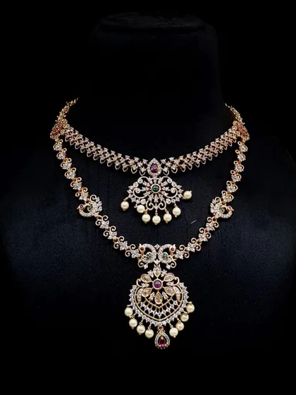 This double-layer AD stone necklace features peacock motifs and pearl drops. It is a beautiful fusion of traditional design and modern sparkle, perfect for a reception or engagement party.