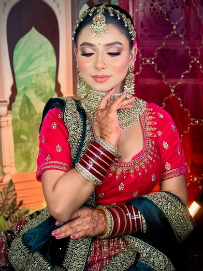 A royal bridal look in a deep pink and velvet lehenga. The makeup is soft yet defined, with a focus on flawless skin.