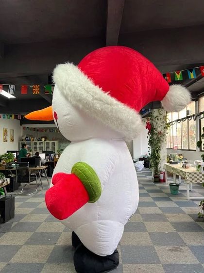 A side view of our inflatable Snowman mascot, complete with a Santa hat and festive mittens. This character is large, cheerful, and perfect for catching attention.