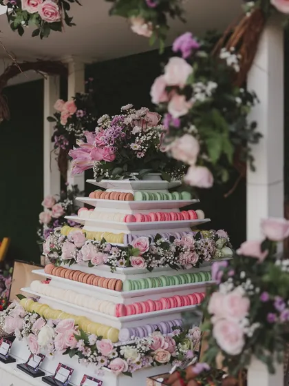 A stunning macaron tower, adorned with fresh flowers. A beautiful and delicious alternative to a traditional cake that also serves as a decor element.