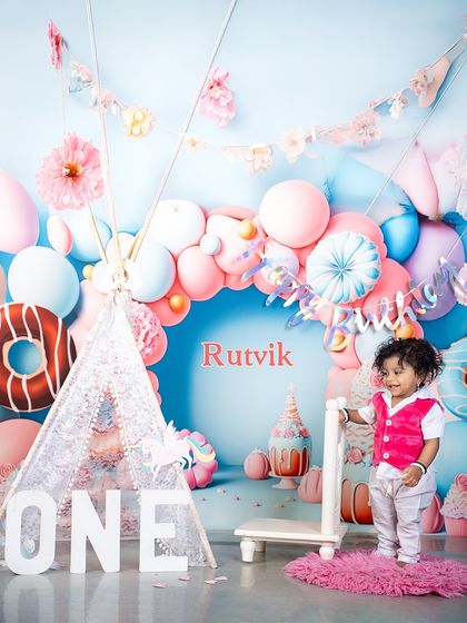 A personalized touch for Rutvik's first birthday! The custom name on the backdrop makes the celebration even more special, surrounded by a whimsical world of donuts and balloons.