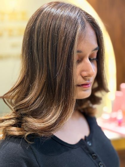 A side profile showcasing the delicate, face-framing highlights of a custom balayage. This technique is perfect for brightening your complexion.