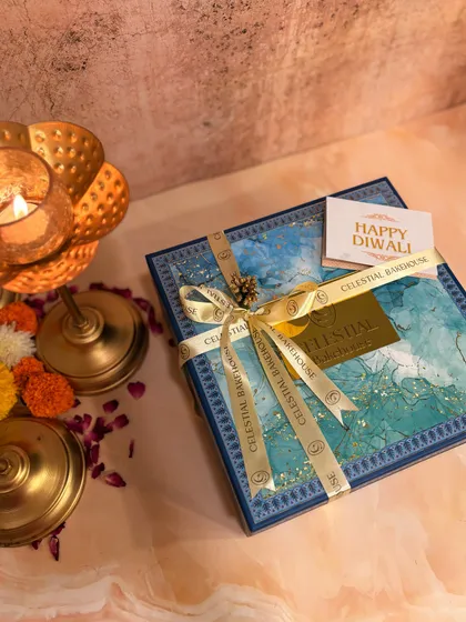 Our Illuminating Indulgence hamper for Diwali, closed and tied with a ribbon. The beautiful blue box with gold accents is designed to capture the festive spirit.