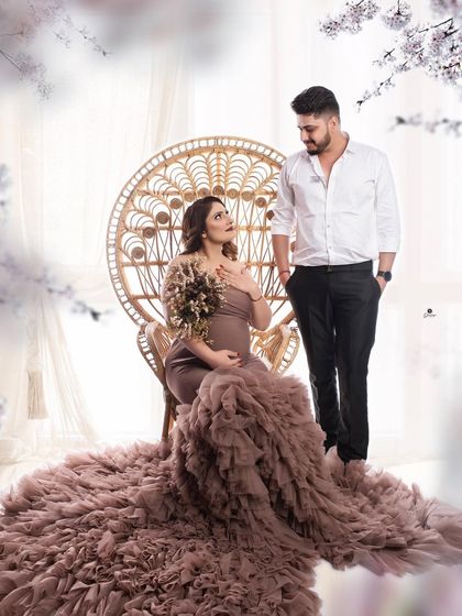 A regal couple portrait featuring the boho peacock chair and a magnificent ruffled gown. The partner stands beside her, creating a look of shared elegance and romance.