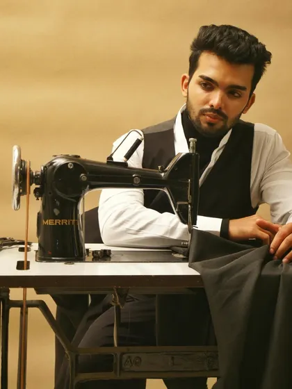 A narrative-driven image showing the model at a sewing machine, as if in the process of creation. This behind-the-scenes style shot is effective for brand storytelling campaigns.